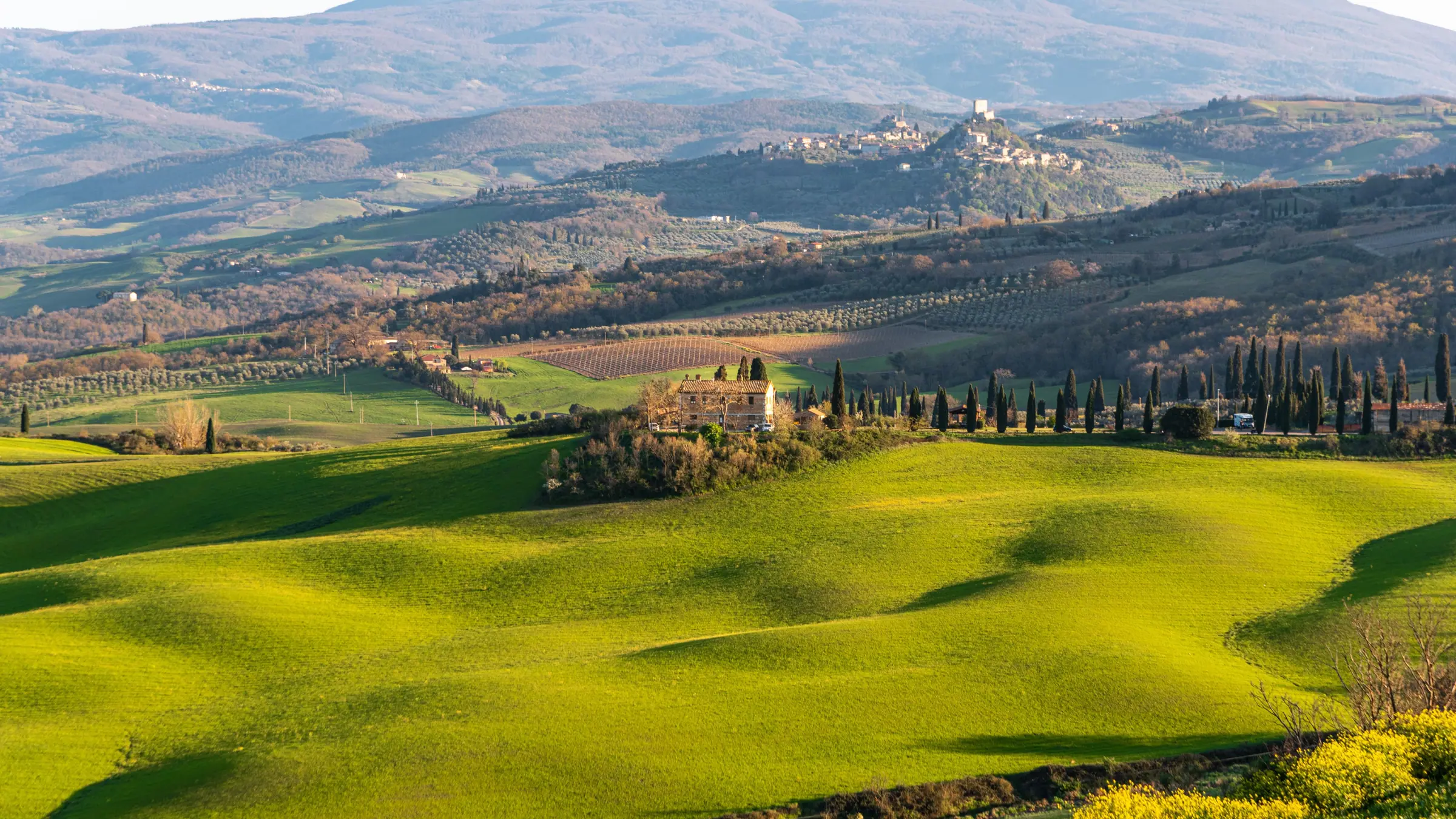 Colline verdi con casale e cipressi nella campagna toscana